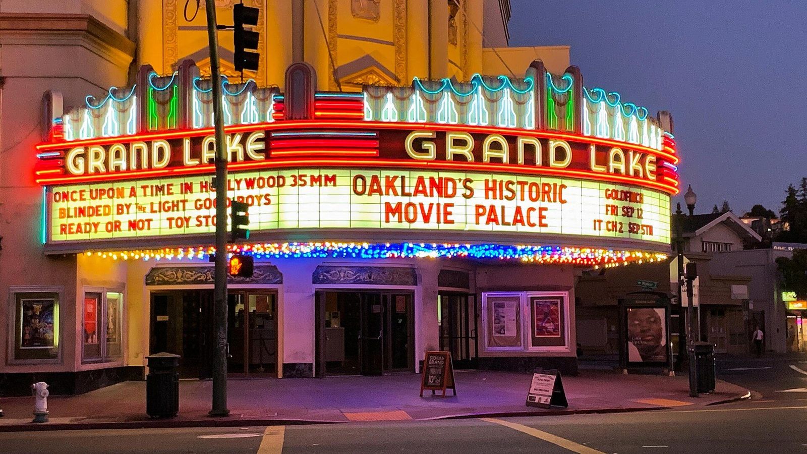 The Grand Lake Theatre's lit marquee at dusk, reading Oakland's Historic Movie Palace